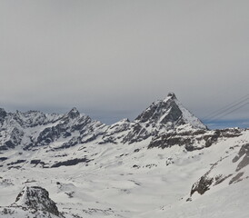 Fototapeta na wymiar Scenic view of Matterhorn mountain from ski slope at Cervino Ski Paradise. Italian side shows cable car route amidst surrounding peaks.