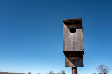 Closeup of a wooden birdhouse against blue sky