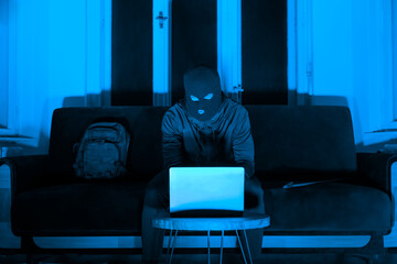 Man on laptop in dark room with blue hue
