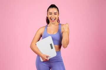 Excited woman with scale celebrating