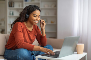 Smiling Black Woman Using Laptop and Headset for Video Call at Home
