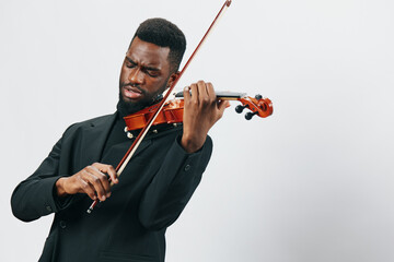 African American man in black suit playing a violin on white background in studio setting
