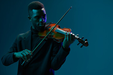 Elegant musician playing the violin in a black suit on a vibrant blue background
