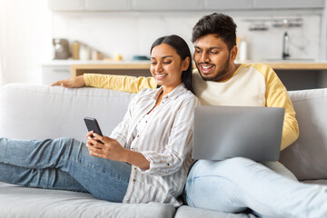 Indian Man and Woman Sitting on Couch Looking at Cell Phone