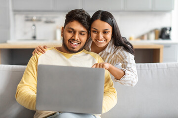 Indian Man and Woman Sitting on Couch Looking at Laptop