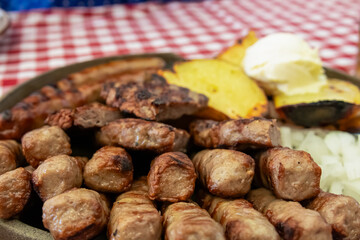 Mixed platter of meat with Cevapcici, sausages and pleskavica served in local restaurant in Maribor, Slovenia. Served with potatoes, onions and pita bread. National dish in traditional shop
