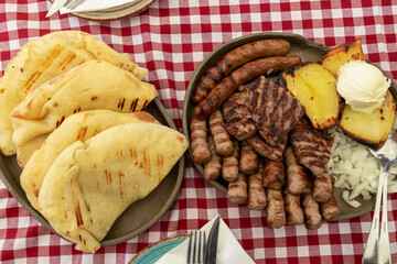 Mixed platter of meat with Cevapcici, sausages and pleskavica served in local restaurant in Maribor, Slovenia. Served with potatoes, onions and pita bread. National dish in traditional shop