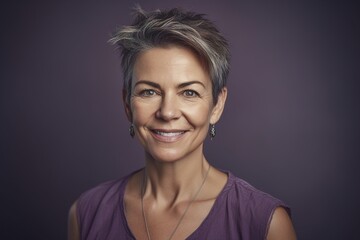 A woman with short hair and a purple shirt is smiling