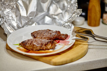 Grilled steak resting under aluminum foil before serving