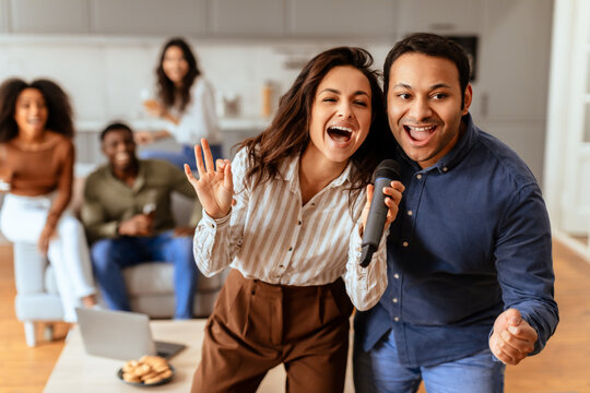 Couple singing enthusiastically into a mic at home
