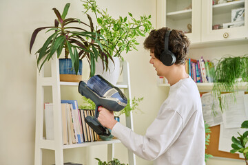 Young man wearing headphones vacuums bookshelves at home