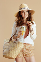 smiling stylish woman in blouse and shorts isolated on beige