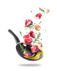 Raw beef meat steaks with garlic and rosemary are falling into a frying pan with oil isolated on white background