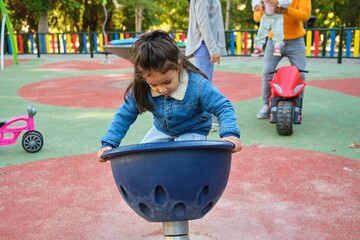Latin three years old boy playing spinner bowl at a playground