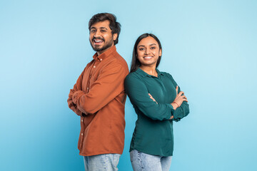 Two people smiling with arms crossed on blue