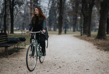 Stylish and confident young woman enjoys a bike ride on a serene park path, exemplifying a blend of leisure and business elegance.