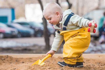A beautiful, cheerful little boy of two years old walks on the playground in the spring. A child is...