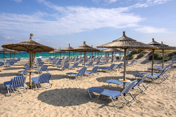Sun loungers on the Marmari beach on the island of Kos. Beautiful sandy beach with turquoise waters. Greece
