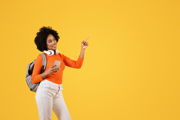 A joyful young woman with curly hair, wearing a bright orange shirt, white pants
