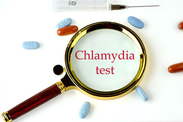 Medical concept. Chlamydia Test text through a magnifying glass on a white background with pills...