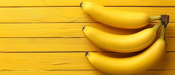   Three bananas atop a yellow wood table, near a yellow planked wall