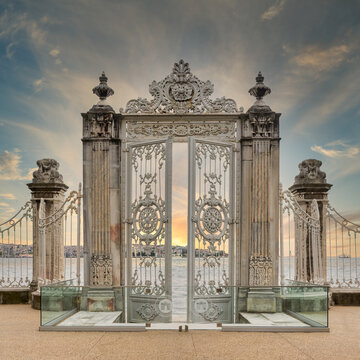 Sunrise shot of pair of half closed elaborately decorated white painted metal gates leading to the opulent Dolmabahce Palace in Istanbul, Turkey, and offering stunning views of the Bosphorus Strait