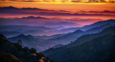 a sunset over a mountain range with a bright orange sun in the distance and a hazy sky above it