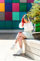 Modern girl with red and green hair with headphones waiting in the faculty