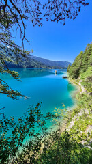 Fototapeta na wymiar Panoramic view of alpine landscape seen from east bank of lake Weissensee in Carinthia, Austria. Tranquil forest in serene landscape amidst remote untouched nature in summer. Pristine turquoise water