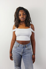 Serious attractive young Black woman with dreadlocks stands on white background