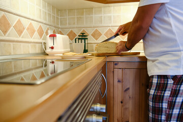Man cutting bread in kitchen at home