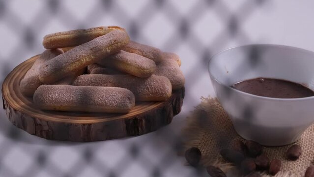 scena che inizia con una griglia metallica che copre parzialmente la scena, poi il video scorre e la scena si apre completamente libera, tazza di cioccolata sul tavolo e  biscotti sul tagliere