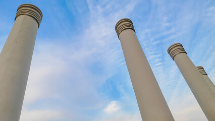 An architectural close-up of pillars touching  the blue sky. Touching the sky.