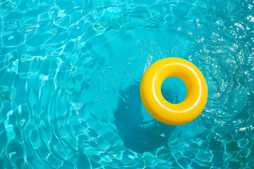 Yellow pool float, ring floating in a refreshing blue swimming pool.
