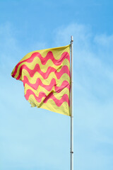 The flag of Tarragona appears vibrant against a blue sky, its red and yellow waves symbolizing the city's rich history and culture.
