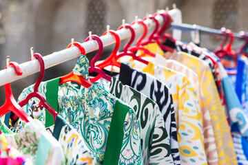 Colorful robes hang on racks, assortment of Bukhara bazaar