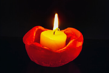 Close up of single burning candle light on black background
