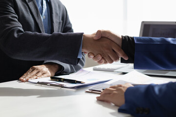Businessmen and investors shake hands as symbol of joint venture after discussing, consulting and...