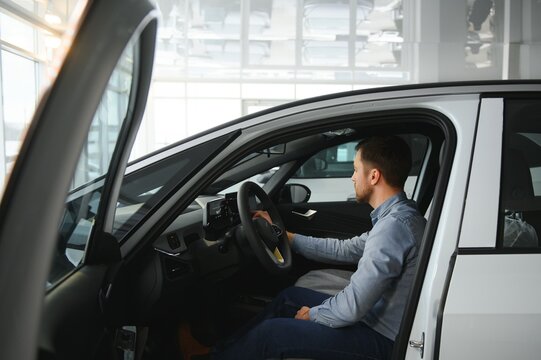 A young man chooses a new car at a car dealership.