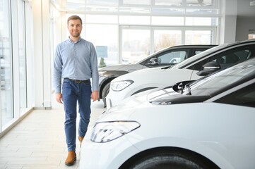 Young man, selling electric cars in the showroom. Concept of buying eco-friendly car for family