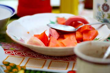 Colorful fruit plate with a spoon on a table with a quirky tablecloth and other utensils