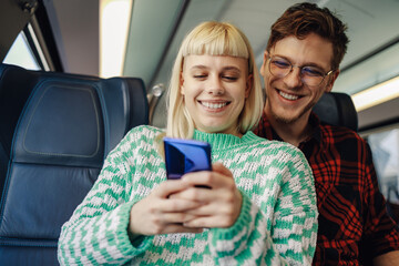 A traveler couple is sending messages on the phone in train.