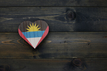 wooden heart with national flag of antigua and barbuda on the wooden background.