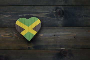 wooden heart with national flag of jamaica on the wooden background.