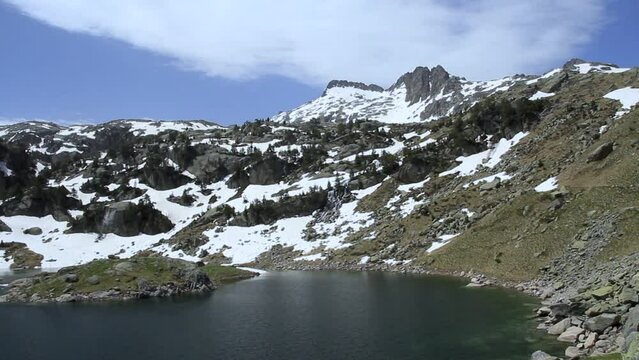 Pico de alta montaña y lago alimentado con agua en primavera. Lago Major de Colomers. Pirineos, Vall d'Aran, Cataluña, España.