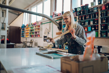 Happy print shop worker using duck tape on screen printing plate.
