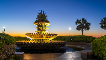 The Pineapple Fountain in Charleston, SC, illuminated at twilight with a crescent moon and Venus in...