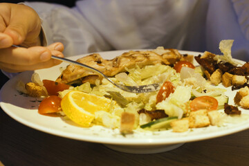 Person Cutting Into Plate of Food With Knife and Fork