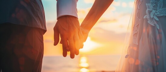 couple holding hands on sunset use wedding dress at beach - obrazy, fototapety, plakaty