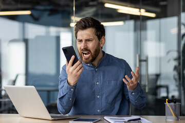 Frustrated businessman arguing on phone at office desk